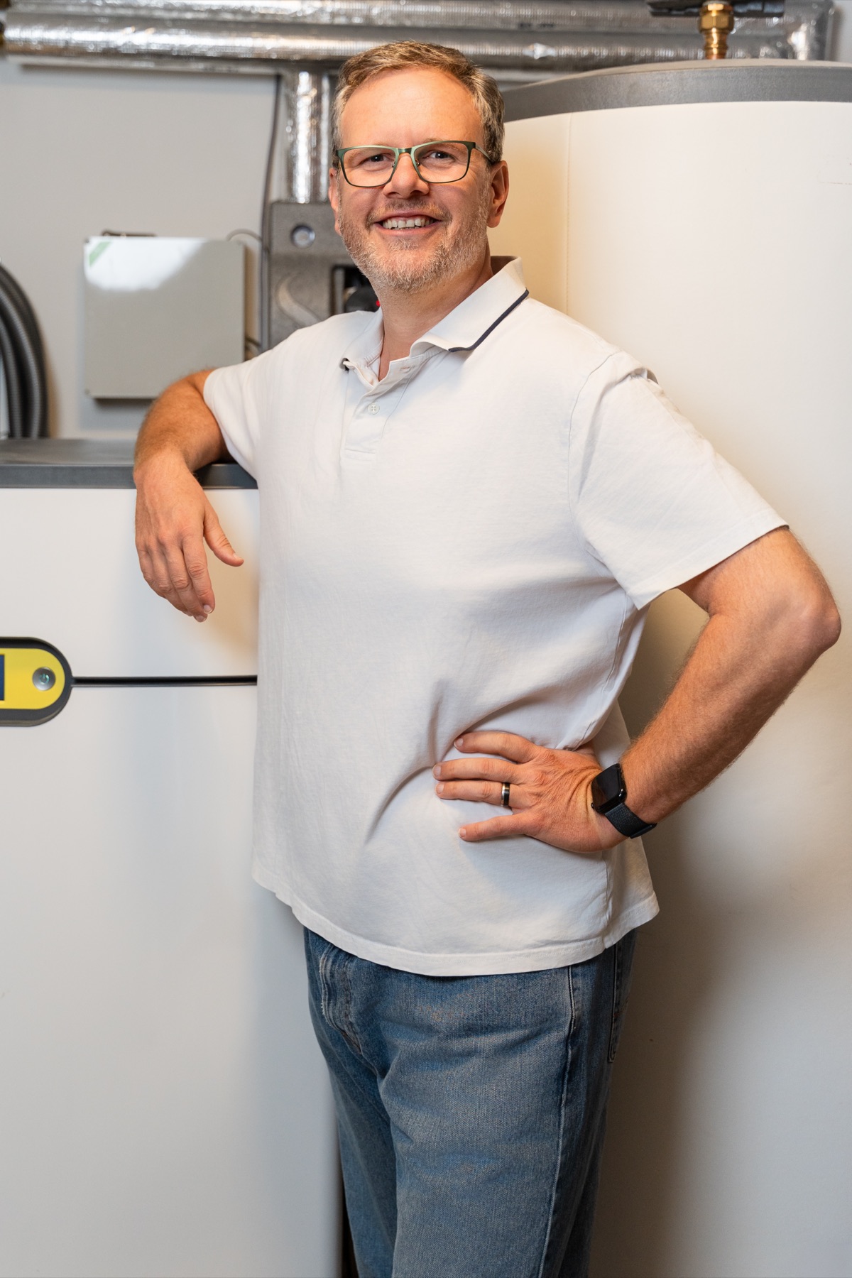 Christian Persch im Heizungsraum neben Pufferspeicher und Wärmepumpentechnik